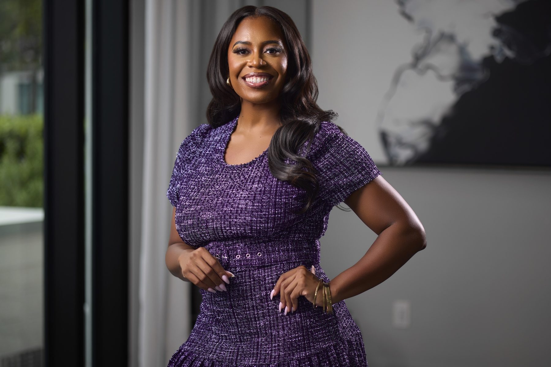 Ashley Mayberry with her hands on her hips in a purple tweed dress